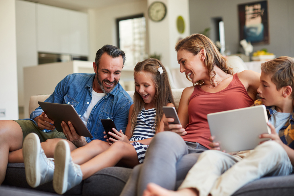 A cheerful family sitting in their cozy living room, all using different devices with a strong Wi-Fi signal.