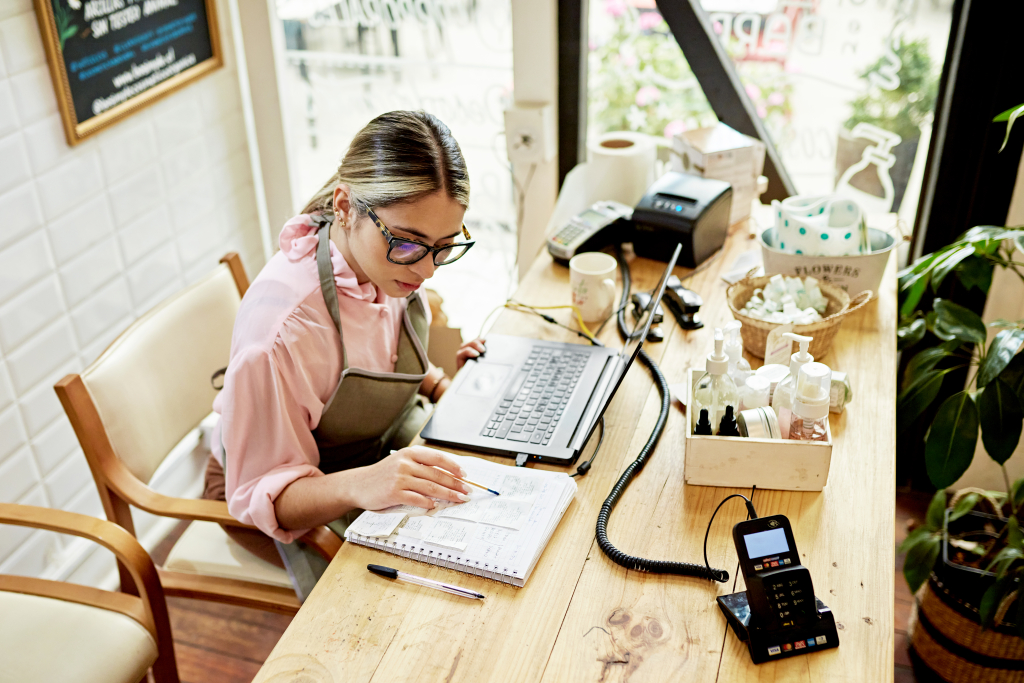 A business owner happily reviewing customer orders on a laptop.