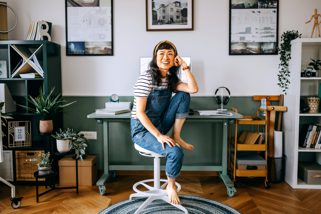 Portrait of cheerful casually clothed beautiful woman sitting at the desk at home office